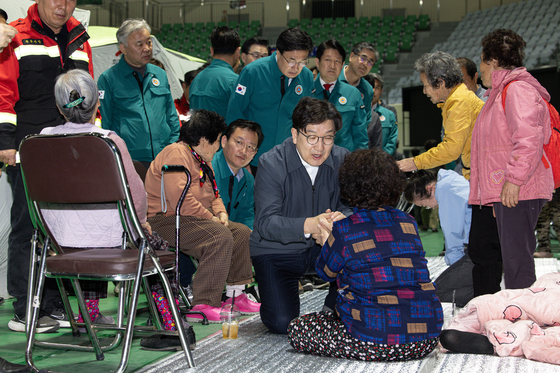 People Power Party floor leader Kweon Seong-dong, center, holds hands with a woman displaced by ongoing wildfires at a shelter in Andong, North Gyeongsang, on March 27. [NEWS1]