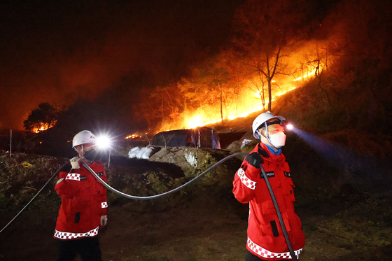 Firefighters contain a wildfire that originated from nearby Uiseong County in Andong City, North Gyeongsang, on March 27. [KIM JONG-HO]