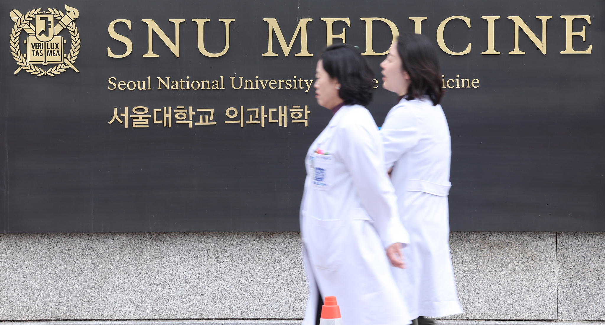 Doctors walk across the Seoul National University College of Medicine campus in Jongno District, central Seoul, on March 27.[NEWS1]