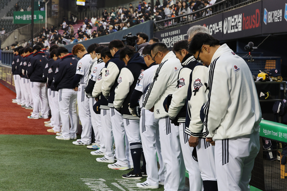 The Doosan Bears stand for a moment of silence ahead of a game against the Kiwoom Heroes at Jamsil Baseball Stadium in southern Seoul on Wednesday.  [YONHAP]
