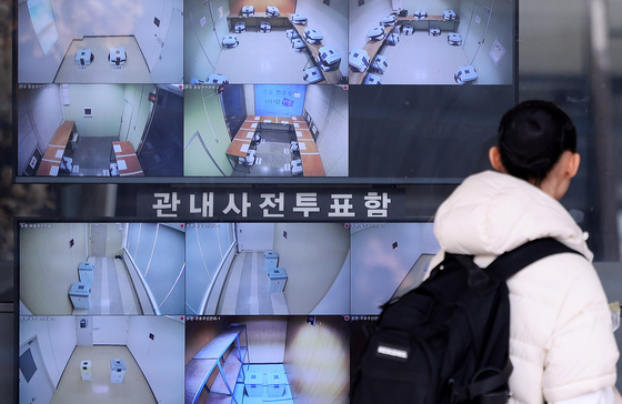 A passerby walks by CCTV screens displaying ballot boxes for early voting in the April 2 by-election for Guro District Office chief at the Seoul branch of the National Election Commission in Jongno District, central Seoul, on March 30. [NEWS1] 