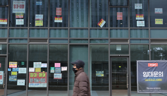 A passerby walks in front of a commercial building with empty spaces and posters reading ″For rent″ on Feb. 25 in Seoul. [YONHAP]