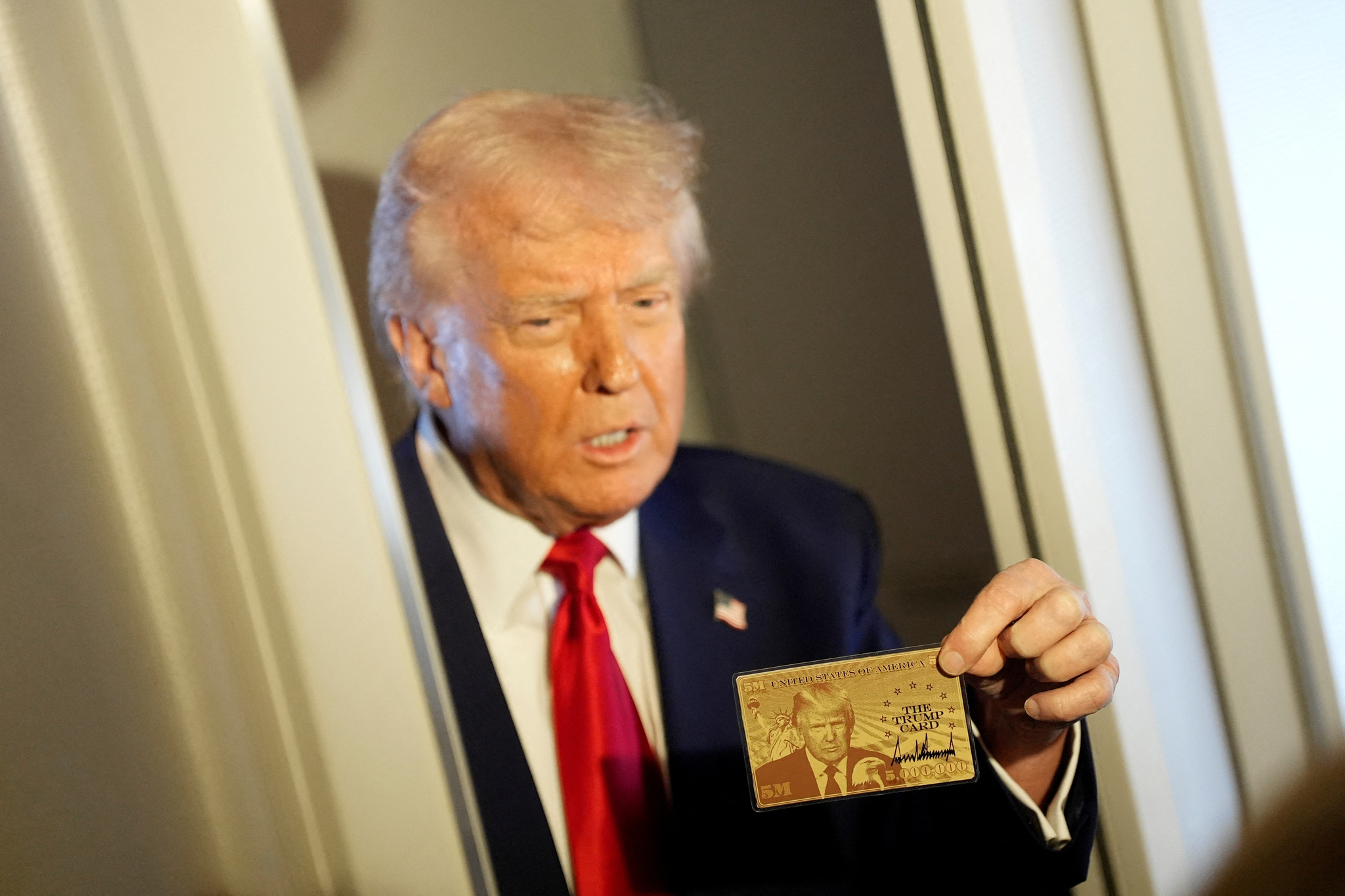 U.S. President Donald Trump holds ″The Trump Card″ as he speaks with journalists onboard Air Force One en route to Miami, Florida, U.S., April 3. [REUTERS/YONHAP]