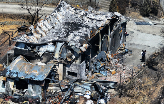 A gas service official inspects a building destroyed by wildfires in the county of Yeongdeok, North Gyeongsang, on April 1. [YONHAP]