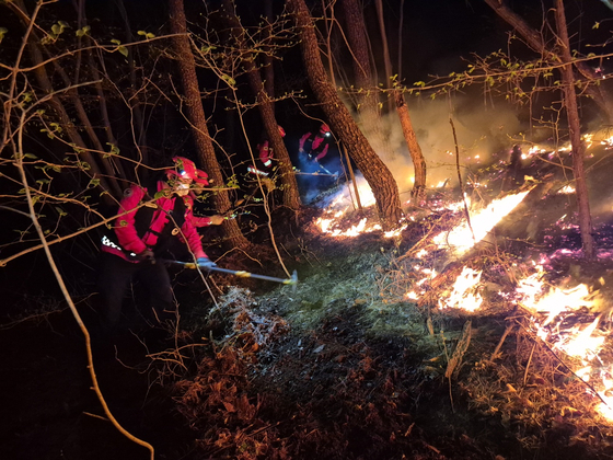 Firefighters and other personnel carry out extinguishing measures at a forested hill in Okjong-myeon, Hadong County, South Gyeongsang, on April 7. [KOREA FOREST SERVICE]