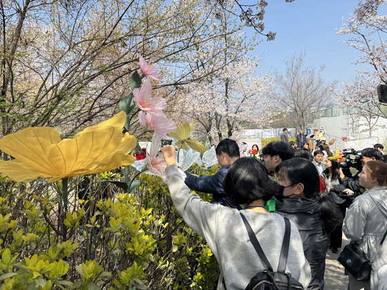 Tour participants touch flower sculptures during Yeongdeungpo District's annual Spring Flower Festival in Yeouido, western Seoul, on April 8. [CHO JUNG-WOO]