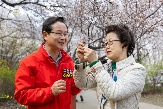 Yeongdeungpo District Office chief Choi Ho-kwon, left, watches a tour member touch flowers during the district's annual Spring Flower Festival in Yeouido, western Seoul, on April 8. [YEONGDEUNGPO DISTRICT OFFICE]