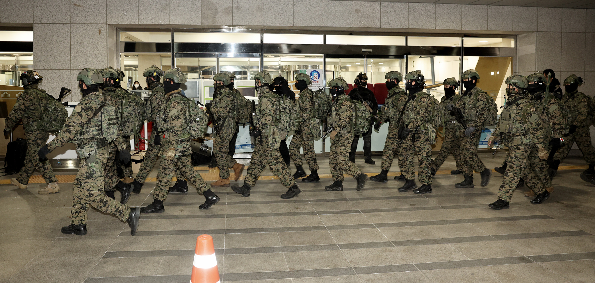 Soldiers passing by the entrace to the main building of the National Assembly in western Seoul on Wednesday, several hours after President Yoon Suk Yeol declared martial law. [JOONGANG ILBO]