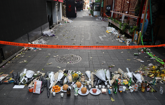 Flowers to pay respects to the victims of the Itaewon tragedy are laid in front of the police's access restriction line near the incident site on Oct. 31, 2022. [YONHAP] 