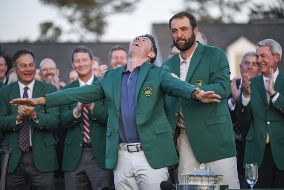 Rory McIlroy, center front, smiles during the Green Jacket and trophy presentation ceremony with Scottie Scheffler following his playoff victory in the final round of the Masters Tournament at Augusta National Golf Club on April 13 in Augusta, Georgia. [GETTY IMAGES]