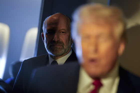 U.S. Commerce Secretary Howard Lutnick listens as U.S. President Donald Trump speaks to reporters while in flight on board Air Force One, en route to Miami on April 3. [AP/YONHAP]