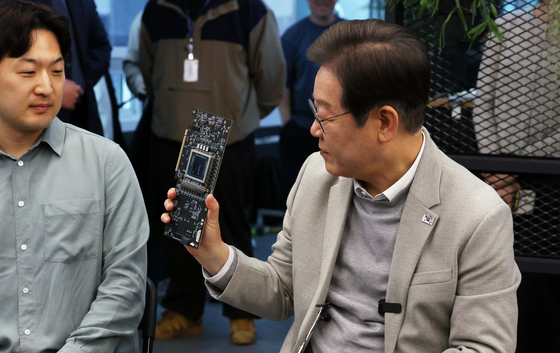 Democratic Party presidential candidate Lee Jae-myung holds a neural processing unit during his visit to local fabless startup FuriosaAI in southern Seoul on April 14. [JOINT PRESS CORPS]