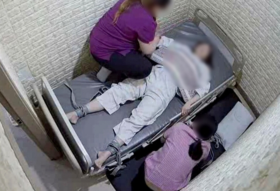 A nursing assistant and caregiver restrain a patient at a psychiatric hospital run by psychiatrist and TV personality Yang Jae-woong in Bucheon, Gyeonggi, on May 27, 2024. [YONHAP]