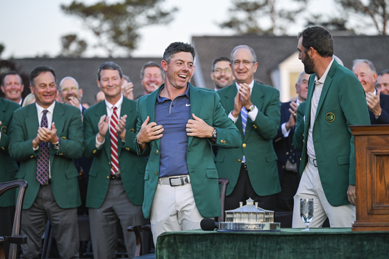 Rory McIlroy, front center, smiles during the Green Jacket and trophy presentation ceremony with Scottie Scheffler following his playoff victory in the final round of the Masters Tournament at Augusta National Golf Club on April 13 in Augusta, Georgia. [GETTY IMAGES]