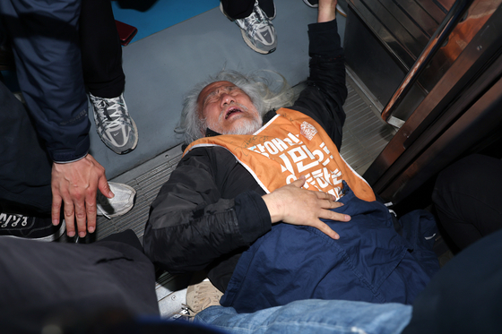 Park Kyoung-seok, chief of the Solidarity Against Disability Discrimination (SADD), lies down across the entrance of subway car at Hyehwa Station, Line 4, as part of SADD's ″We Take the Subway to Work″ campaign on April 21. [NEWS1]