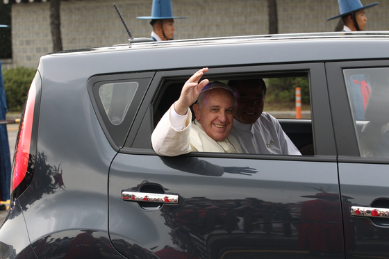 Pope Francis waves to the crowd while riding in the back seat of a Kia Soul during a visit to Korea in 2014. [JOONGANG ILBO]