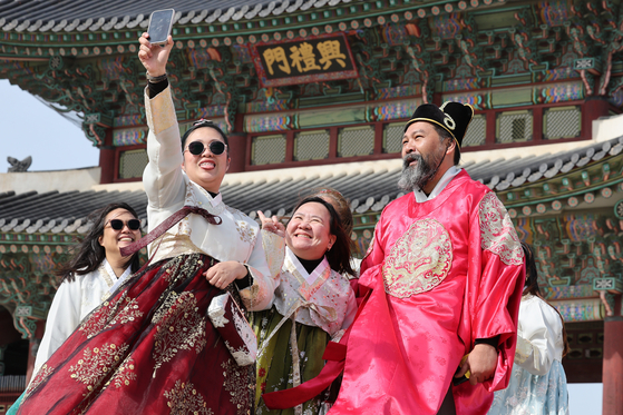 Tourists dressed in hanbok, or as traditional Korean dress, take selfies at Gyeongbok Palace in central Seoul on March 3, as visitors enjoyed the last day of a three-day weekend to mark the March 1 Independence Movement holiday. [NEWS1]