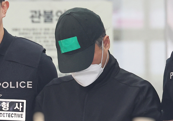 A man in his 50s who allegedly murdered five members of his family including his parents, wife and two daughters is escorted out of Yongin Dongbu Police Precinct to be handed over to prosecutors on April 24. [YONHAP]