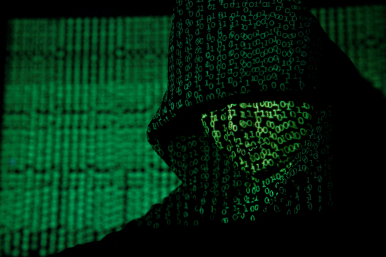 A projection of cyber code on a hooded man is pictured in this illustration picture taken on May 13, 2017. [REUTERS/YONHAP]