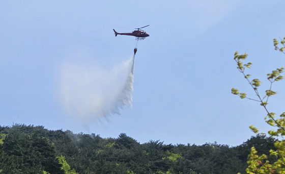 A helicopter drops water to prevent possible reignition in Inje County, Gangwon, on April 27. [NEWS1]