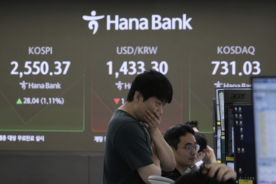 A currency trader watches monitors near a screen showing the Korea Composite Stock Price Index, top left, and the foreign exchange rate between dollar and Korean won, top center, at the foreign exchange dealing room of the KEB Hana Bank headquarters in central Seoul on April 25. [AP/YONHAP]