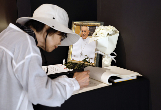 A woman writes a message in a condolence book for the late Pope Francis at the Holy See Pavilion of Expo 2025 in Osaka, Japan, on April 24. [EPA/YONHAP]