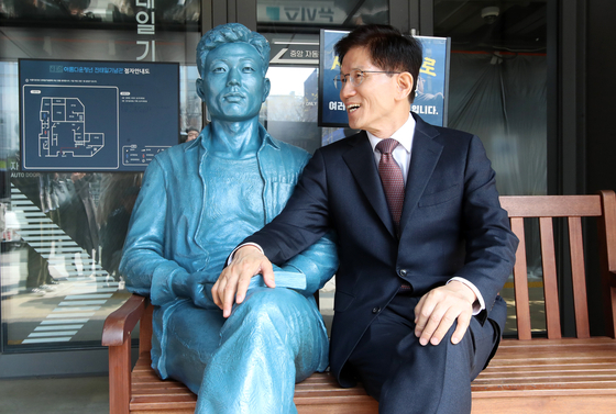 People Power Party presidential primary candidate Kim Moon-soo sits next to the statue of labor rights activist Jeon Tae-il in Jongno District, central Seoul, on April 10. [JOINT PRESS CORPS] 