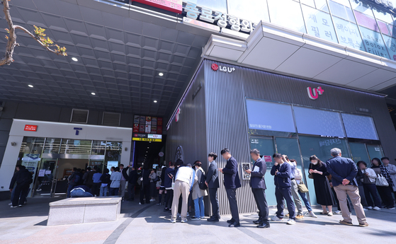 People line up outside a SK Telecom store in Seoul to replace their SIM cards on April 28. [YONHAP]