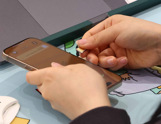 A SK Telecom retail store employee changes the SIM card for a phone at a branch in Seoul on April 28. [YONHAP] 