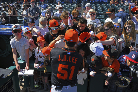 Baseball fans swarm San Francisco Giants outfielder Lee Jung-hoo as he signs autographs before the start of a spring training baseball game against the Texas Rangers in Surprise, Arizona on Feb. 22. [AP/YONHAP] 