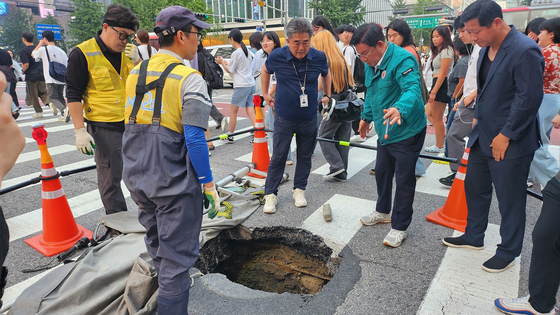 Government officials visit a road subsidence site in Mapo District, western Seoul, and oversee restoration efforts on April 14. [NEWS1] 
