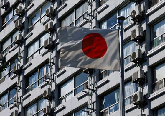 Air conditioner outdoor units are fixed on the outer wall of an apartment building while a Japanese national flag flutters in Tokyo, Japan, June 28, 2022. [REUTERS/YONHAP]