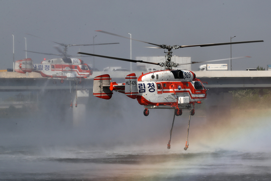 On the morning of April 29, the second day of the wildfire on Mount Hamji in Daegu’s Buk District, a firefighting helicopter draws water from the nearby Geumho River. [NEWS1]