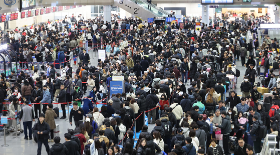 Crowds of travelers wait in line to depart at Gimhae International Airport ahead of the Lunar New Year holidays on Jan. 26. [JOONGANG PHOTO]