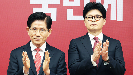 People Power Party presidential candidates Kim Moon-soo, left, and Han Dong-hoon clap after the party announces the two finalists for its primary at party headquarters in Yeouido, western Seoul, on April 29. [JOINT PRESS CORPS]
