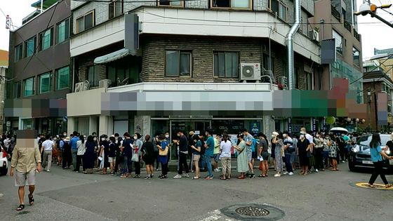 Customers are lined up outside the headquarters of Mergeplus on the afternoon of Aug. 13, 2021, in Yeongdeungpo, western Seoul, demanding refunds after the company reduced the number of affiliated shops and stopped selling Mergemoney on Aug. 11, 2021. [NEWS1]