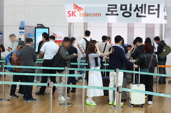 Travelers line up to change their SIM cards at the SK Telecom roaming center in the departure hall of Terminal 1 at Incheon International Airport in Incheon on May 4. [YONHAP]