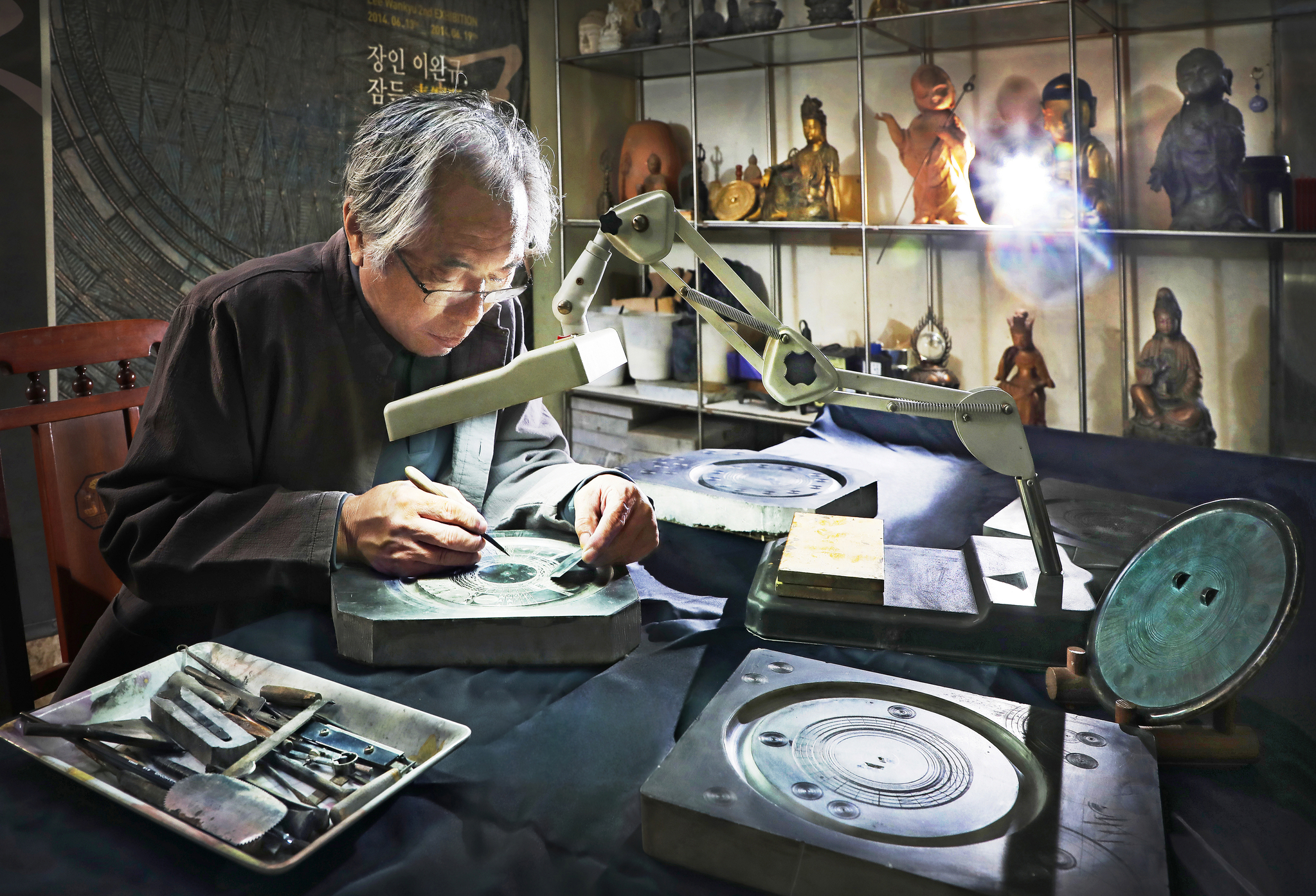 Lee Wan-kyu demonstrates reproducing Danyusemungyeong, a bronze mirror with geometric patterns, at his studio in Yongin, Gyeonggi. [PARK SANG-MOON]