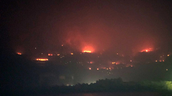 Flames rise over the coastal village of Seok-ri in Yeongdeok County, North Gyeongsang, on March 29, as a wildfire that began in Uiseong spreads with strong winds. [NEWS1]
