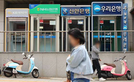 Pedestrians pass by ATM machines for Korea's major banks in Seoul on May 5. [YONHAP] 