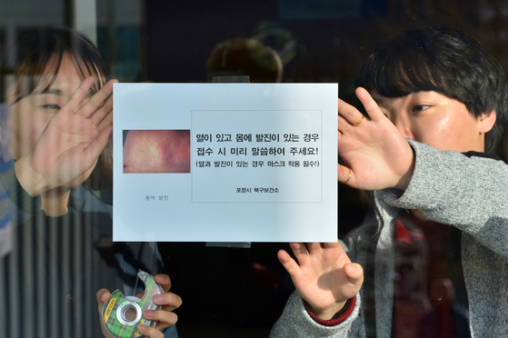 Staff at the Pohang Buk District Health Center in Pohang, North Gyeongsang post a notice at the entrance with information about suspected measles symptoms on Jan. 14, 2019. [NEWS1]