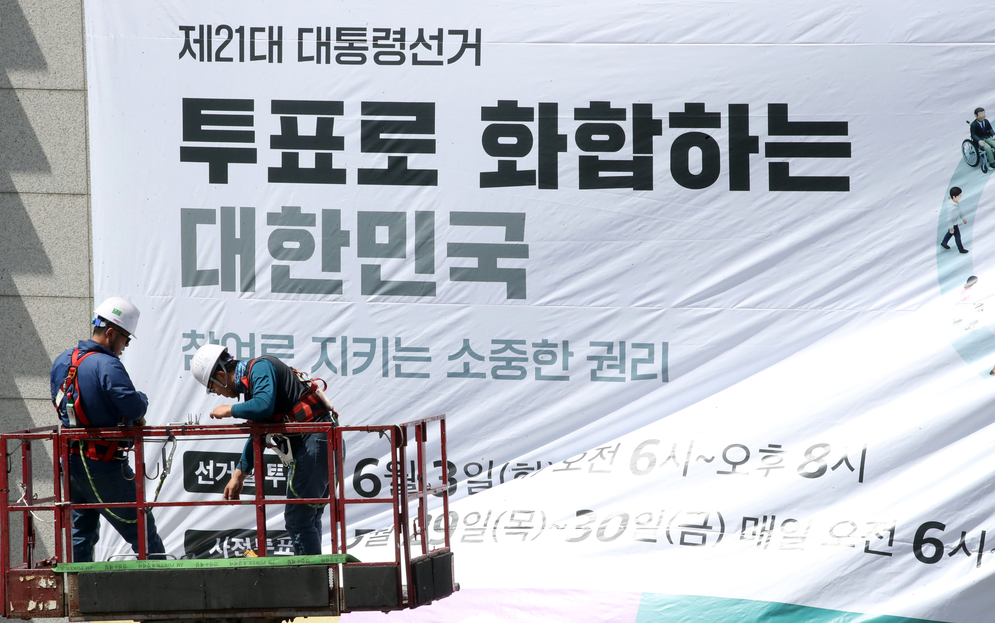 Workers hang up banners encouraging participation in the upcoming 21st presidential elections at a building in Jeju on May 8. [NEWS1]