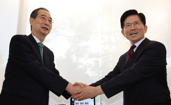 Han Duck-soo, left, independent presidential candidate, shakes hands with Kim Moon-soo, presidential candidate for the conservative People Power Party in a restaurant in Jongno District, central Seoul, on May 7. [YONHAP]