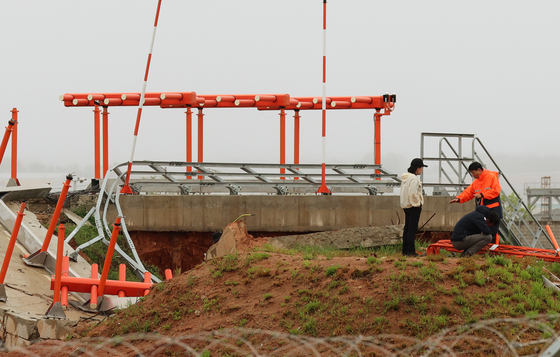 Officials from the Korea Aviation and Railway Accident Investigation Board (Araib) under the Ministry of Land, Infrastructure and Transport inspect the damaged localizer mound at the site of the Jeju Air crash at Muan International Airport on April 22. [YONHAP]