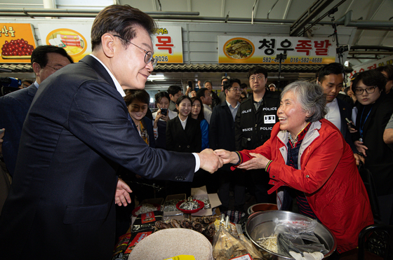Democratic Party presidential candidate Lee Jae-myung, left, shakes hands with a resident while campaigning in Changnyeong County, South Gyeongsang, on Saturday. [NEWS1]