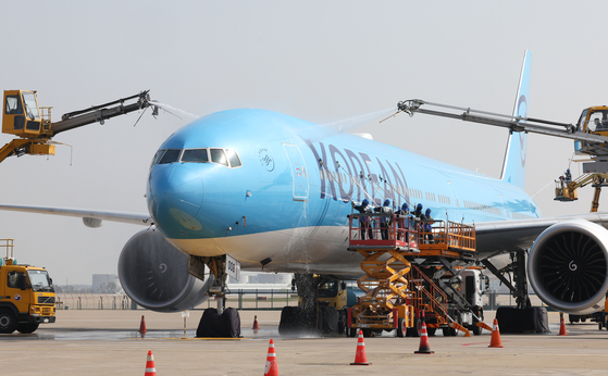 Korean Air employees wash the fuselage of a Boeing 777-300ER aircraft, HL8008, in front of the maintenance hangar in Incheon on April 24. [YONHAP]