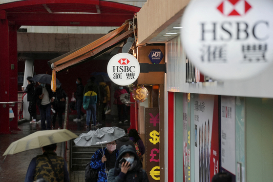 Pedestrians wearing face masks following the Covid-19 outbreak, walk past a HSBC bank branch in Hong Kong on Feb. 22, 2022. [REUTERS/YONHAP]