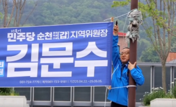 Democratic Party lawmaker Kim Moon-soo removes a promotional banner bearing his name in a photo shared on his official Facebook account on May 11. [SCREEN CAPTURE]