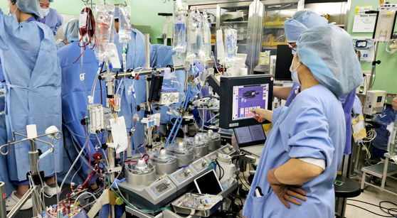  Clinical perfusionist Oh Ji-young monitors the patient’s condition during surgery. Behind the heart-lung machine, Professor Jung Ui-seok and his team perform the operation. Cardiac surgeries typically require two perfusionists working together. [CHAE HYE-SEON]