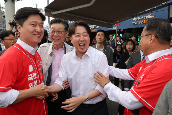 Reform Party presidential candidate Lee Jun-seok, second from right, shakes hands with People Power Party lawmaker Woo Jae-jun at a market in Daegu. [YONHAP]